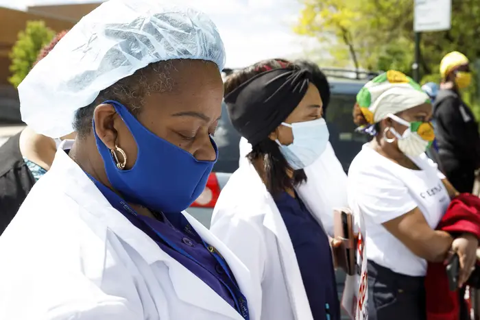 Nurses dressed in hospital gear bow their heads to pause for a moment silence for a Rikers Island nurse, William Chan, who died from COVID-19 during a rally organized by the New York State Nurses Association at the entrance to the Rikers Island correctional facility to protest and draw attention to the handling of COVID-19 patients and healthcare worker conditions at the prison in Queens in May.